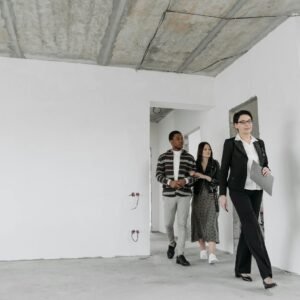 Real estate agent showing an unfinished house to potential buyers during a viewing session.